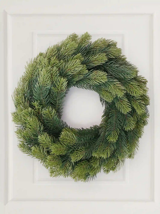 Artificial Christmas wreath, 60 cm, made of lifelike fir branches, hanging on white wall paneling