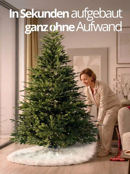 Frau befestigt den weißen Plüsch-Baumrock mit Klettverschluss am Stamm eines künstlichen Weihnachtsbaums.