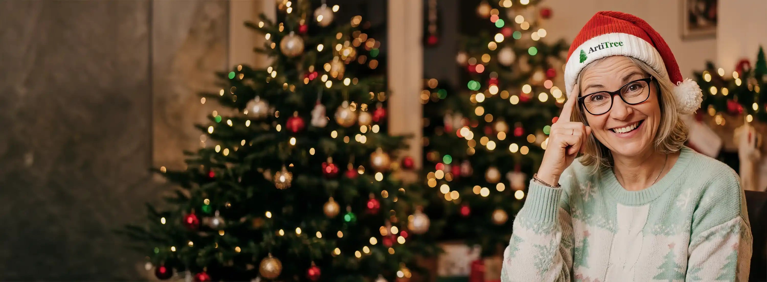 Frau mit Weihnachtsmütze von ArtiTree steht neben künstlichen Weihnachtsbäumen